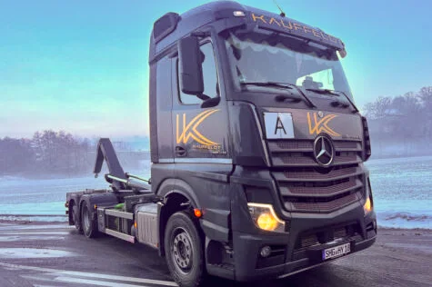 Abroll-LKW der Firma Kauffeldt vor einem stimmungsvoll mit Nebel verhangenem Feld auf einer landstraße