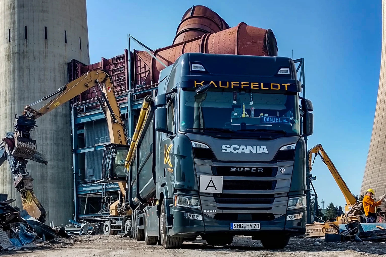 Schüttguttransporter der Firma Kauffeldt wird auf einer Baustelle von einem Bagger mit Schrott beladen